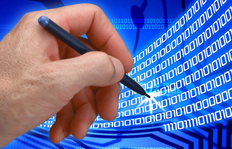 Ręka z długopisem przed kodem zerojedynkowym Fot. Freeimages