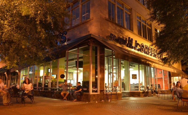 Kawiarnia i goście przy stolikach przed nią.