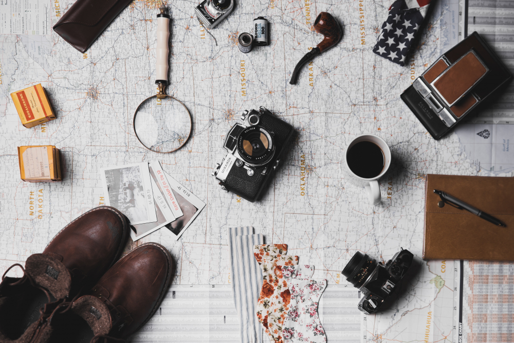 Mapa, lupa, aparaty, rolki filmowe, buty, notes Photo by ian dooley on Unsplash